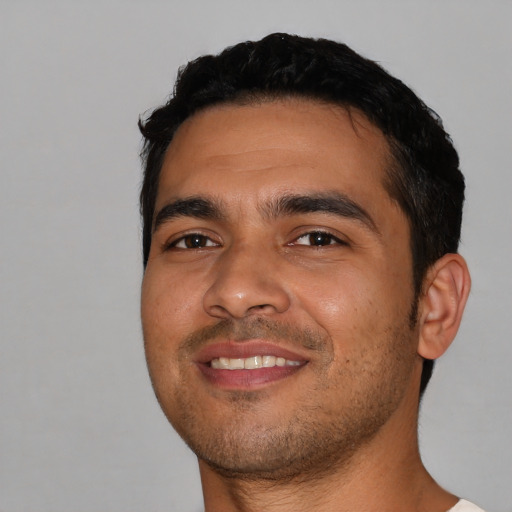 Joyful latino young-adult male with short  black hair and brown eyes