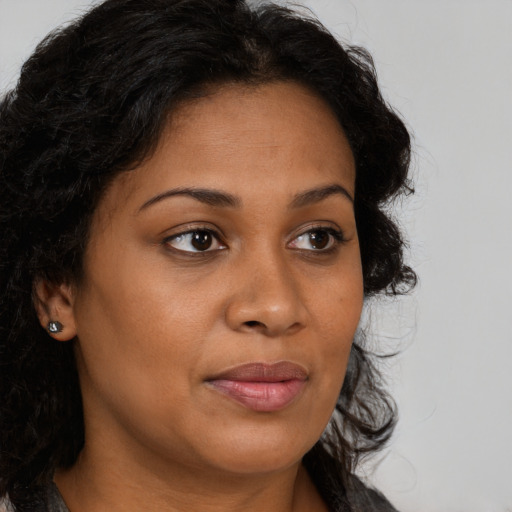 Joyful black young-adult female with long  brown hair and brown eyes