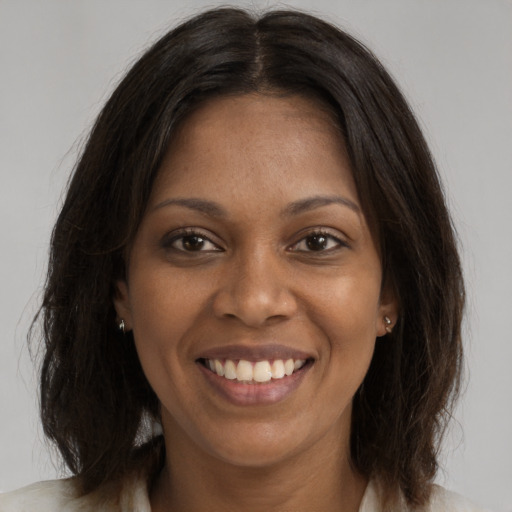 Joyful black young-adult female with long  brown hair and brown eyes