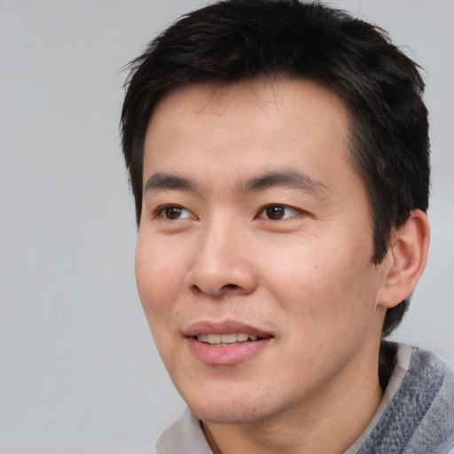 Joyful asian young-adult male with short  brown hair and brown eyes