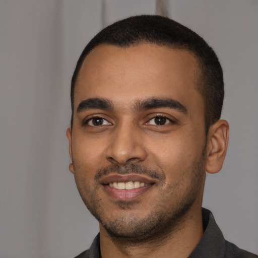 Joyful black young-adult male with short  black hair and brown eyes