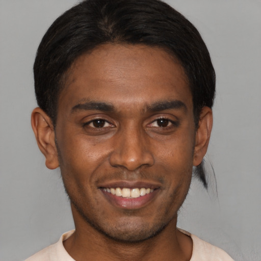 Joyful black young-adult male with short  brown hair and brown eyes