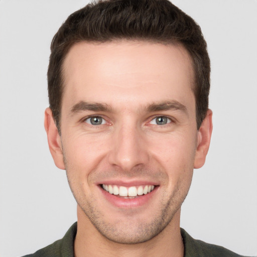 Joyful white young-adult male with short  brown hair and grey eyes