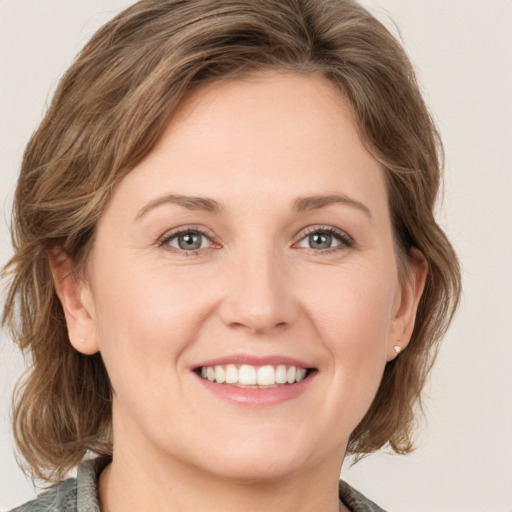 Joyful white young-adult female with medium  brown hair and green eyes