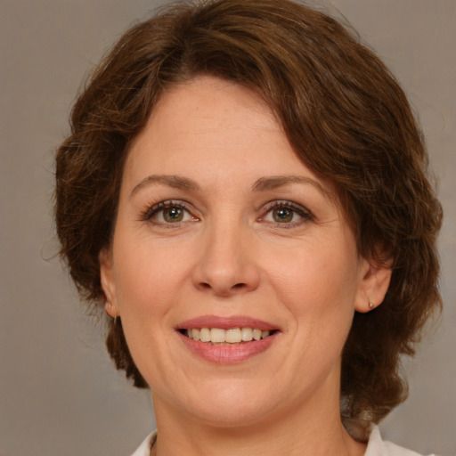 Joyful white adult female with medium  brown hair and green eyes