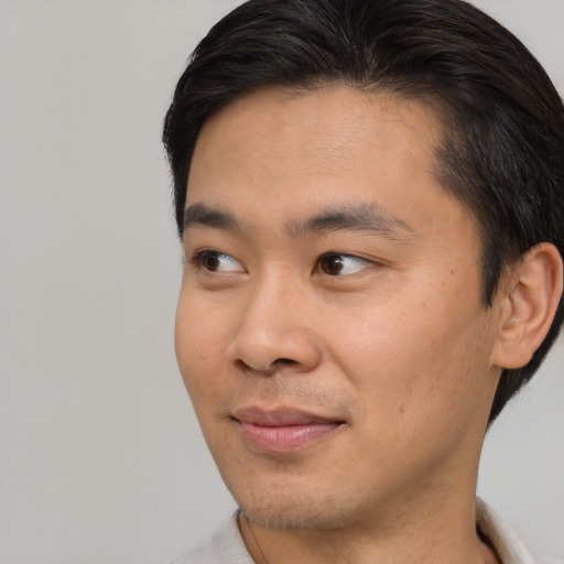 Joyful asian young-adult male with short  brown hair and brown eyes