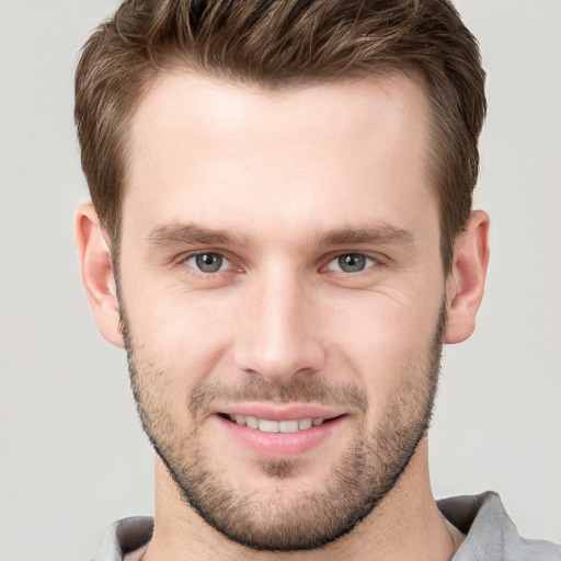 Joyful white young-adult male with short  brown hair and grey eyes