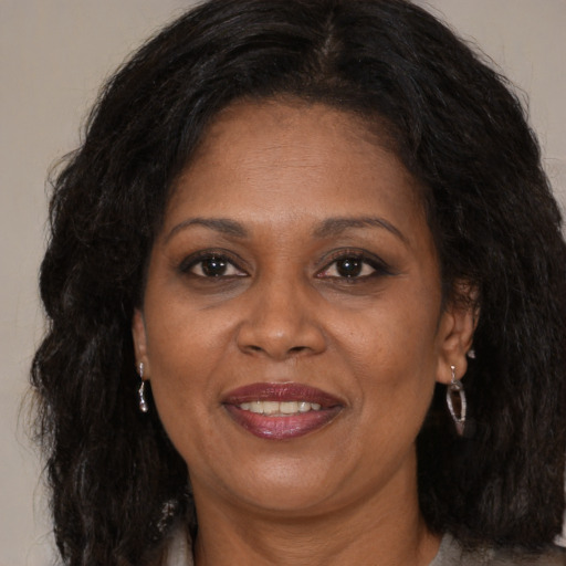 Joyful black adult female with long  brown hair and brown eyes