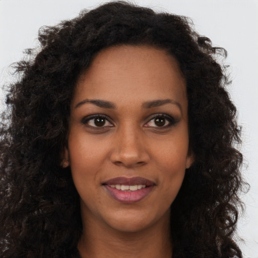 Joyful black young-adult female with long  brown hair and brown eyes