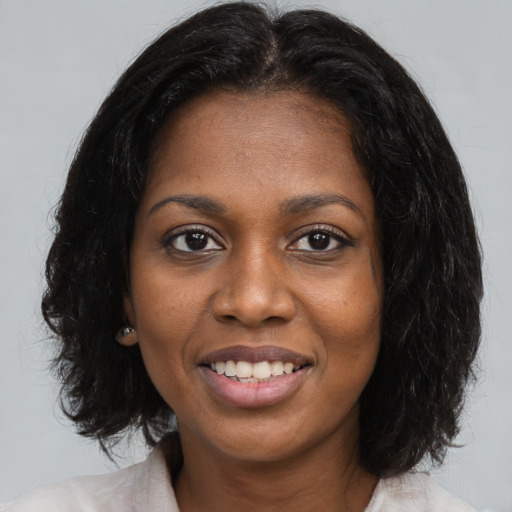 Joyful black young-adult female with long  brown hair and brown eyes