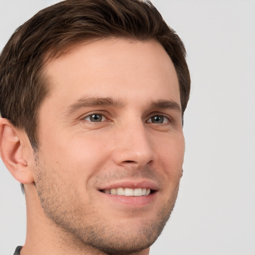 Joyful white young-adult male with short  brown hair and grey eyes