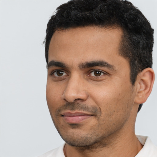 Joyful latino young-adult male with short  black hair and brown eyes
