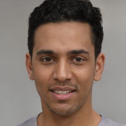 Joyful latino young-adult male with short  black hair and brown eyes