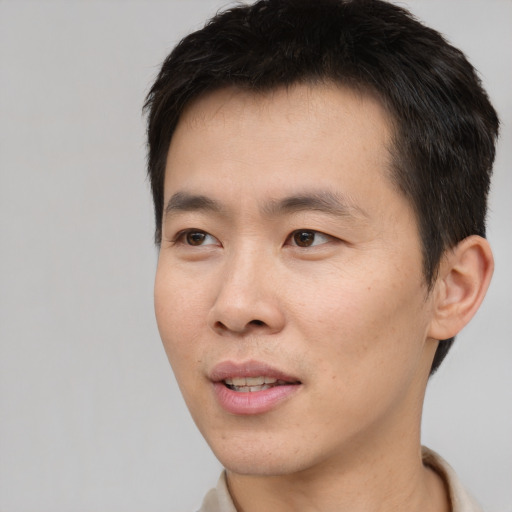 Joyful asian young-adult male with short  black hair and brown eyes