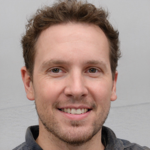 Joyful white adult male with short  brown hair and grey eyes