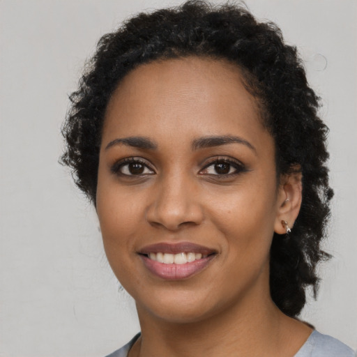 Joyful black young-adult female with long  brown hair and brown eyes