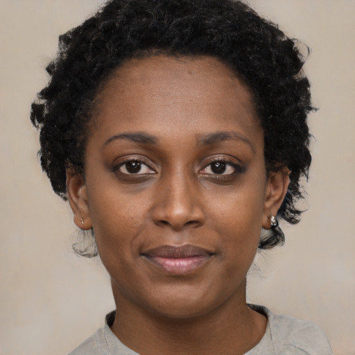 Joyful black young-adult female with short  black hair and brown eyes