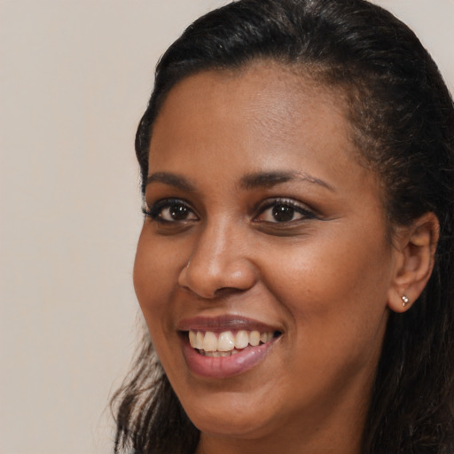 Joyful black young-adult female with long  brown hair and brown eyes