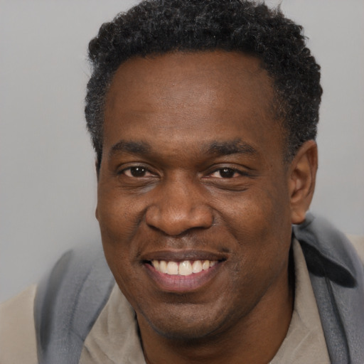 Joyful black adult male with short  brown hair and brown eyes