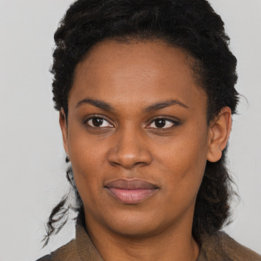 Joyful black young-adult female with short  black hair and brown eyes