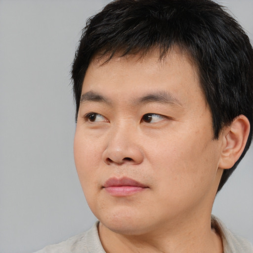 Joyful asian young-adult male with short  black hair and brown eyes