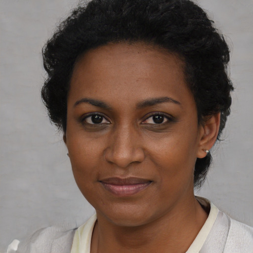 Joyful black young-adult female with short  black hair and brown eyes