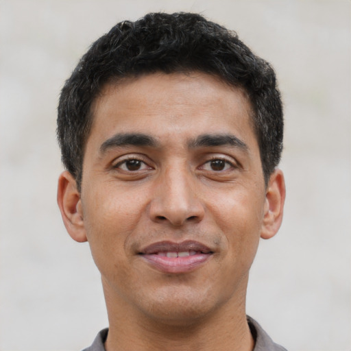Joyful latino young-adult male with short  brown hair and brown eyes