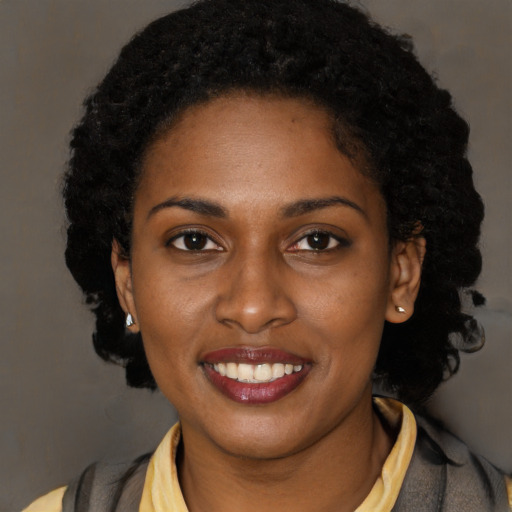 Joyful black young-adult female with long  brown hair and brown eyes