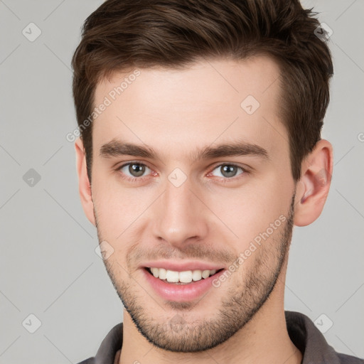 Joyful white young-adult male with short  brown hair and grey eyes