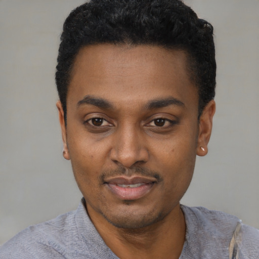 Joyful black young-adult male with short  black hair and brown eyes