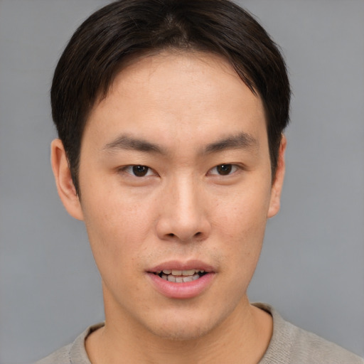 Joyful asian young-adult male with short  brown hair and brown eyes