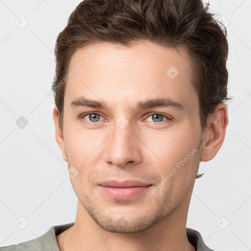 Joyful white young-adult male with short  brown hair and grey eyes