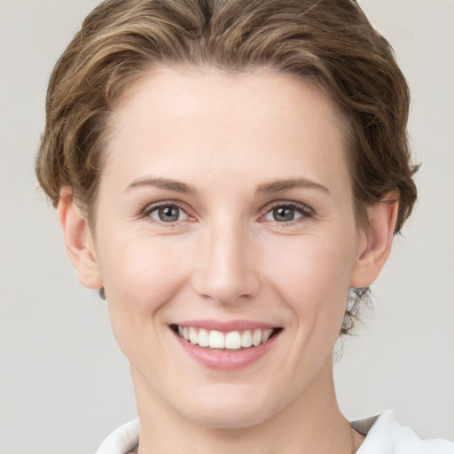 Joyful white young-adult female with short  brown hair and green eyes