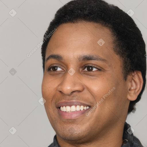 Joyful black young-adult male with short  black hair and brown eyes