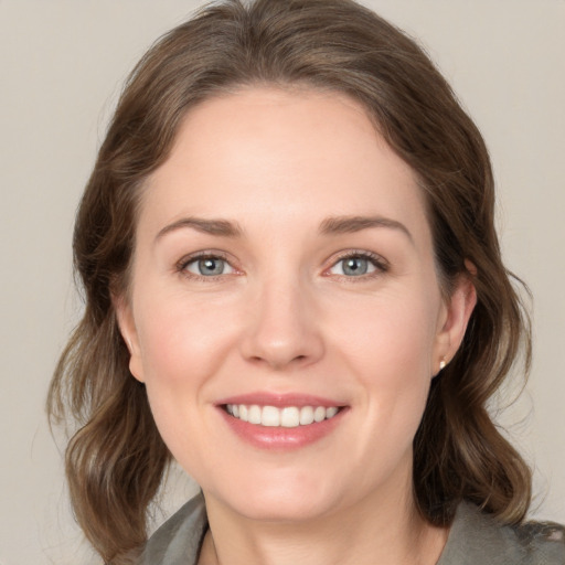 Joyful white young-adult female with medium  brown hair and grey eyes