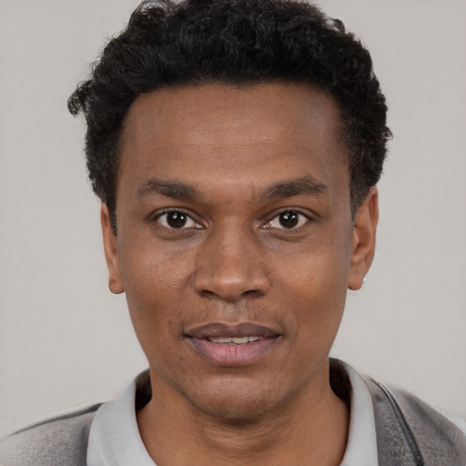 Joyful black young-adult male with short  black hair and brown eyes