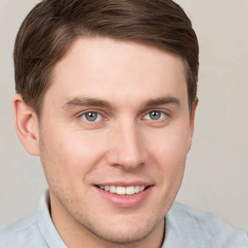 Joyful white young-adult male with short  brown hair and grey eyes