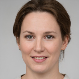 Joyful white young-adult female with medium  brown hair and green eyes