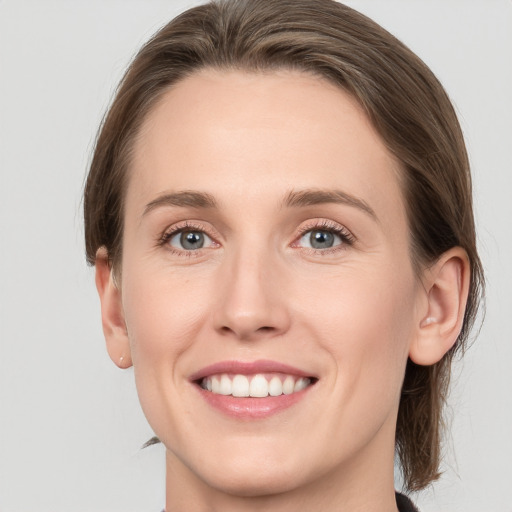 Joyful white young-adult female with medium  brown hair and grey eyes