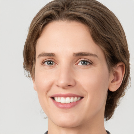 Joyful white young-adult female with medium  brown hair and green eyes