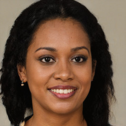 Joyful black young-adult female with long  brown hair and brown eyes