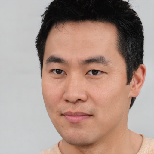 Joyful asian young-adult male with short  black hair and brown eyes