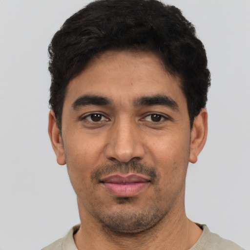 Joyful latino young-adult male with short  black hair and brown eyes