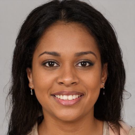 Joyful black young-adult female with long  brown hair and brown eyes