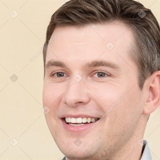 Joyful white young-adult male with short  brown hair and grey eyes