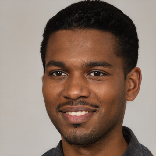 Joyful black young-adult male with short  black hair and brown eyes