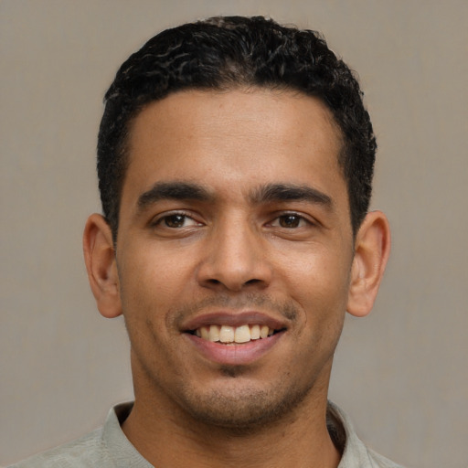 Joyful latino young-adult male with short  black hair and brown eyes