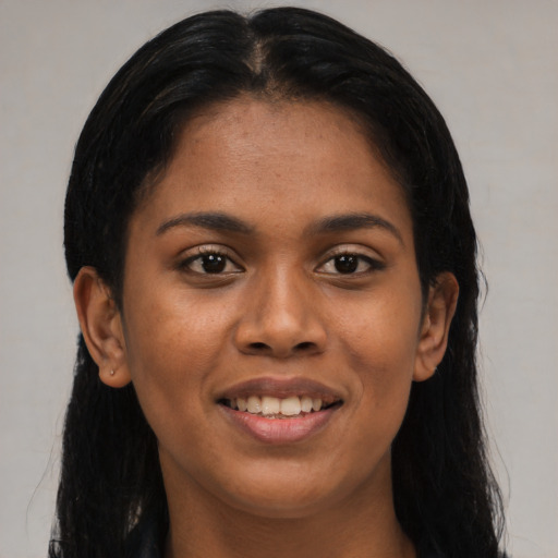 Joyful black young-adult female with long  brown hair and brown eyes