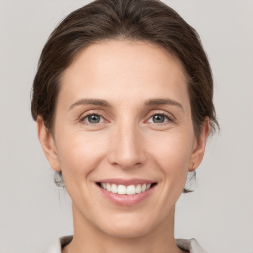 Joyful white young-adult female with medium  brown hair and grey eyes