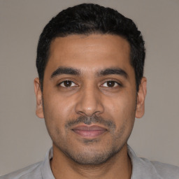 Joyful latino young-adult male with short  black hair and brown eyes